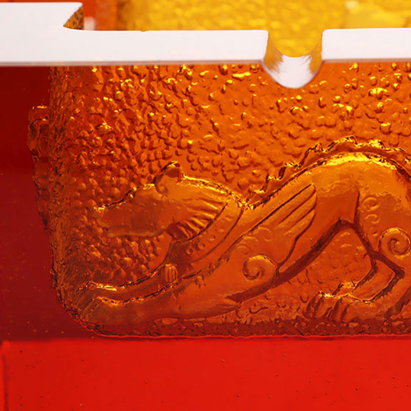 Punainen lasinen tuhkakuppi upeilla kohokuvioiduilla eläinkuvioilla